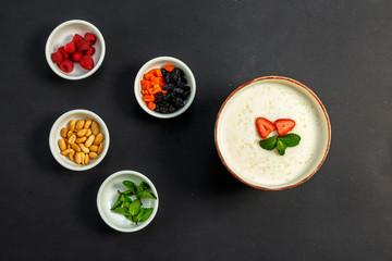 Obraz na płótnie Canvas rice porridge with milk, healthy breakfast with raisins, nuts, mint on a white plate