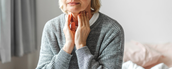 Sick senior adult elderly women touching the neck feeling unwell coughing with sore throat...