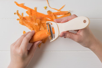 The child carefully cleans the carrots with a special knife.