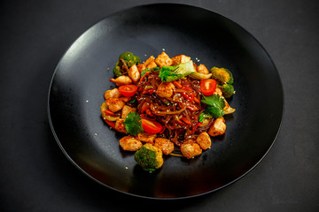 Thai cuisine, rice noodles with chicken, broccoli, tomatoes and greens