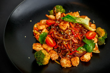 Thai cuisine, rice noodles with chicken, broccoli, tomatoes and greens
