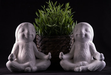 Pair of white smiling sloth ornaments posed in the sitting lotus meditating position with a...