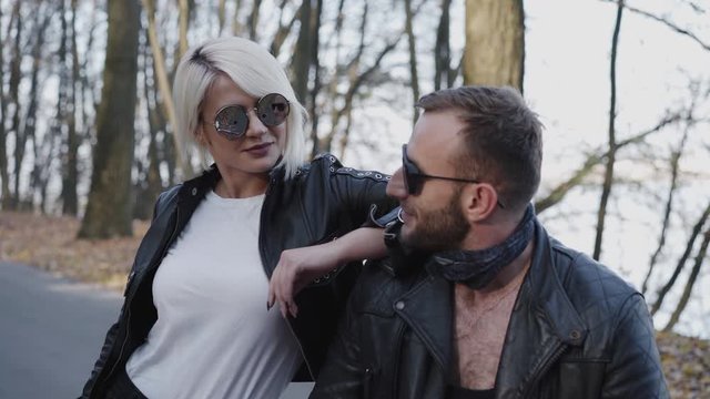 Portrait of stylish blonde and brutal man looking on each other in park