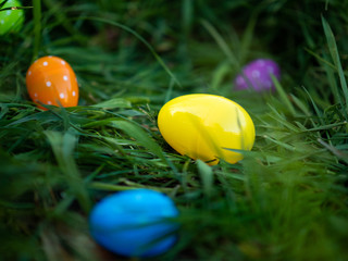 Big yellow Easter egg sitting with scattered polka dotted eggs in the grass