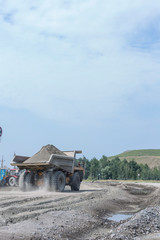 Obraz premium Mining industry: Heavy mining truck driving through the granite ore opencast