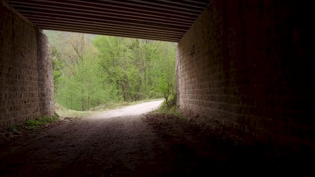 Dolly Tracking Pov Front Shot View Of moving in dark tunnel on dirt road toward light and a beautiful nature