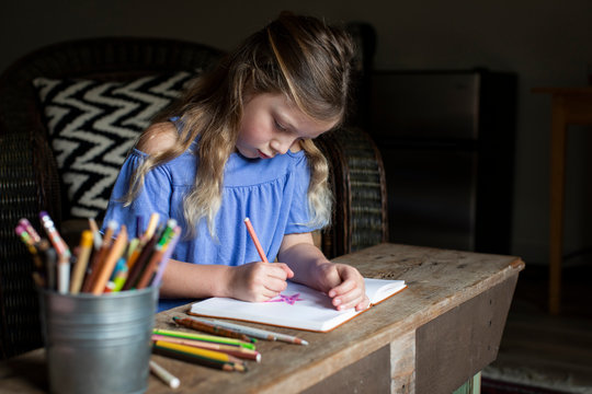 A child draws in a notebook alone during social distancing