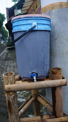 a blue plastic bucket filled with clean water on a bamboo table. used to wash hands to prevent covid-19 virus in Indonesia