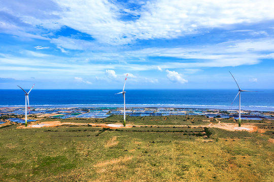 Aerial view of  wind turbines beside sea and coastal road Cam Ranh - Mui Dinh - Ca Na on a sunny day, Phuoc Dinh, Phan Rang, Ninh Thuan, Vietnam. Mui Dinh lighthouse 3 km away from here