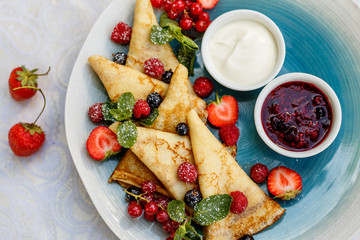 pancakes with fresh berries, jam and sauce on the decorated table