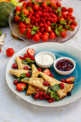pancakes with fresh berries, jam and sauce on the decorated table