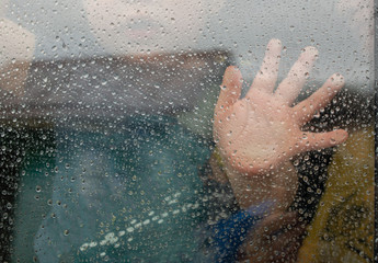Quarantine, stay home. Sad child touches window with his hand