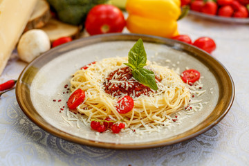 Pasta bolognese with minced meat and tomatoes with greens on the decorated table
