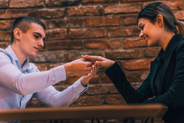 Handsome man putting engagement ring on his girlfriend's hand after marriage proposal