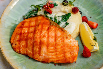 Grilled fish with mashed potatoes and vegetables on the decorated table