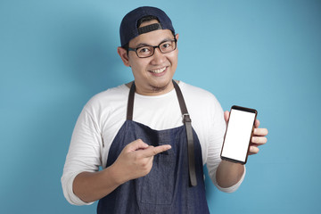 Portrait of Asian male chef or waiter looks happy and proud showing empty copy space smart phone, presenting blank phone template