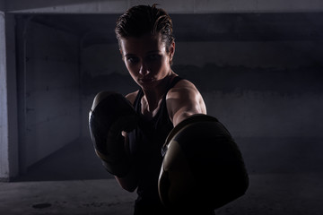 Fototapeta na wymiar Silhouette portrait of young woman punching with boxing gloves