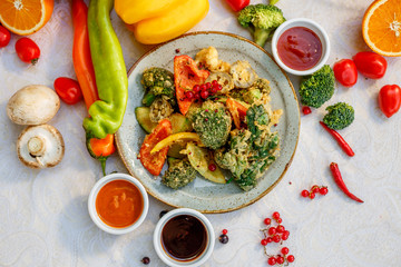 broccoli fried in breading with vegetables with sauces on a decorated table
