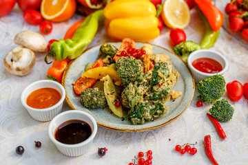 broccoli fried in breading with vegetables with sauces on a decorated table