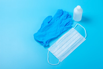 A disposable medical mask,one white bottle of antiseptic, and a blue latex glove on a blue background. The concept of use means protection from germs