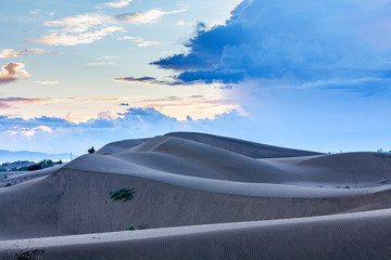 Cham women in traditional dress walking across sand dunes to collecting water at Nam Cuong sand...