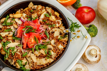 buckwheat with mushrooms, green onions and vegetables on the decorated table