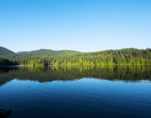 Fototapeta na wymiar Lake surrounded by rainforest in a sunny day of British Columbia province, Canada.