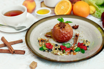Dessert, baked apple with honey mint and strawberries on a white table