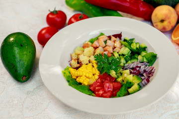 Healthy food, salad with shrimps, tomatoes, corn and avocado on a white table