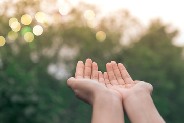 Woman hands place together like praying in front of nature green  background.