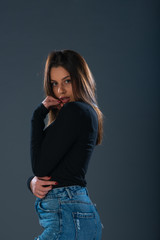 Beautiful young female model in jeans on dark background