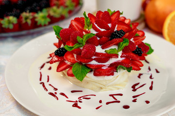 Pavlova dessert with cream mint and strawberry in a white plate on a white table