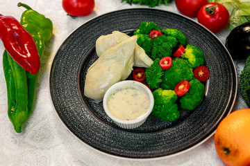 boiled chicken breast with broccoli and tomatoes with sauce, healthy food in a white plate on a white table