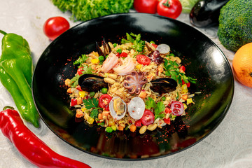 seafood risotto with octopus, shrimp and mussels with tomatoes healthy food in a white plate on a white table