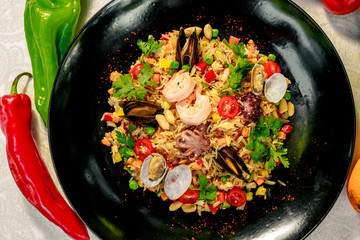 seafood risotto with octopus, shrimp and mussels with tomatoes healthy food in a white plate on a white table