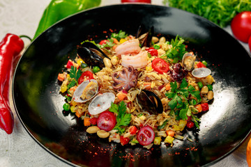 seafood risotto with octopus, shrimp and mussels with tomatoes healthy food in a white plate on a white table