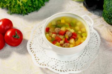 soup with meat balls, potatoes and vegetables in a white plate on a white table