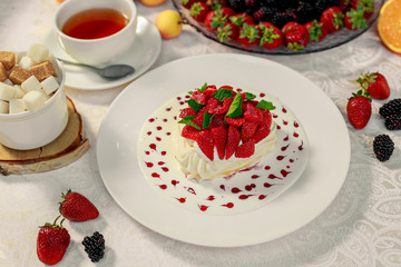 Pavlova dessert with cream mint and strawberry in a white plate on a white table