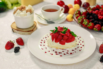 Pavlova dessert with cream mint and strawberry in a white plate on a white table