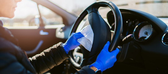 Woman disinfecting the inside of a car with antibacterial wet wipes.
