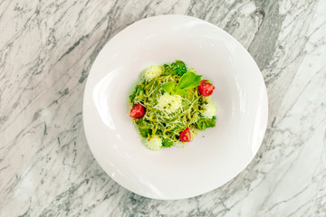 Italian pasta with cheese and vegetables on a white plate