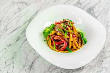 spaghetti with meat and vegetables on a white plate