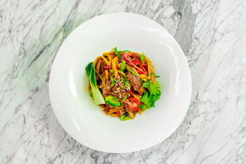 spaghetti with meat and vegetables on a white plate