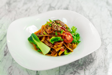 spaghetti with meat and vegetables on a white plate