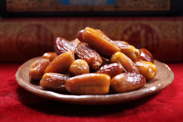 Dates fruit and Islamic Book Koran on carpet background, Islamic background in mosque