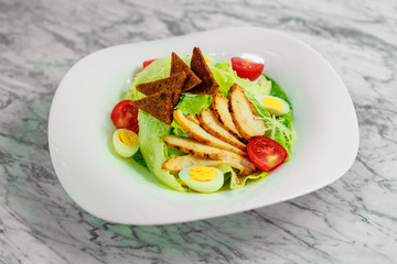 salad with chicken breast slices and vegetables on a white plate, beautiful serving