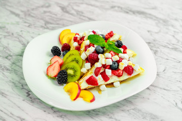 Belgian waffles with nuts, chocolate and fruit on a white plate, beautiful serving