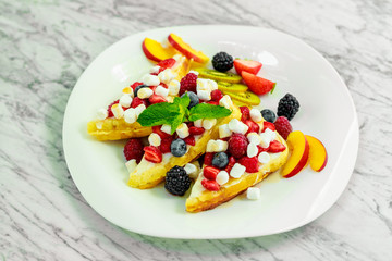 Belgian waffles with nuts, chocolate and fruit on a white plate, beautiful serving