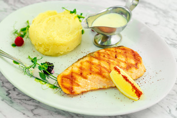 fried salmon fish with mashed potatoes and lemon on a white plate