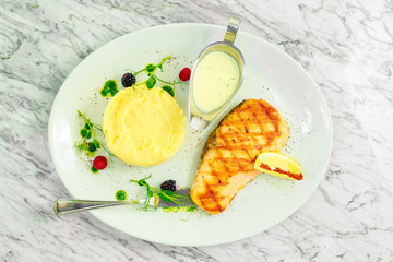 fried salmon fish with mashed potatoes and lemon on a white plate